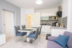 A modern apartment with a dining area, kitchenette, and a living space with a sofa. - Apartment Sea View (Labin)