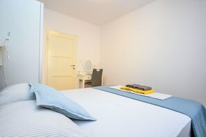 Une chambre à coucher avec un lit, une table de chevet, un miroir et une porte.