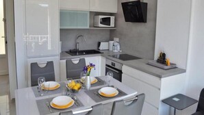 A modern kitchen with white cabinetry, a microwave, and a coffee maker. - Apartment Sea View (Labin)
