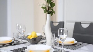 A dining table set with plates, glasses, and a vase with a yellow rose. - Apartment Sea View (Labin)