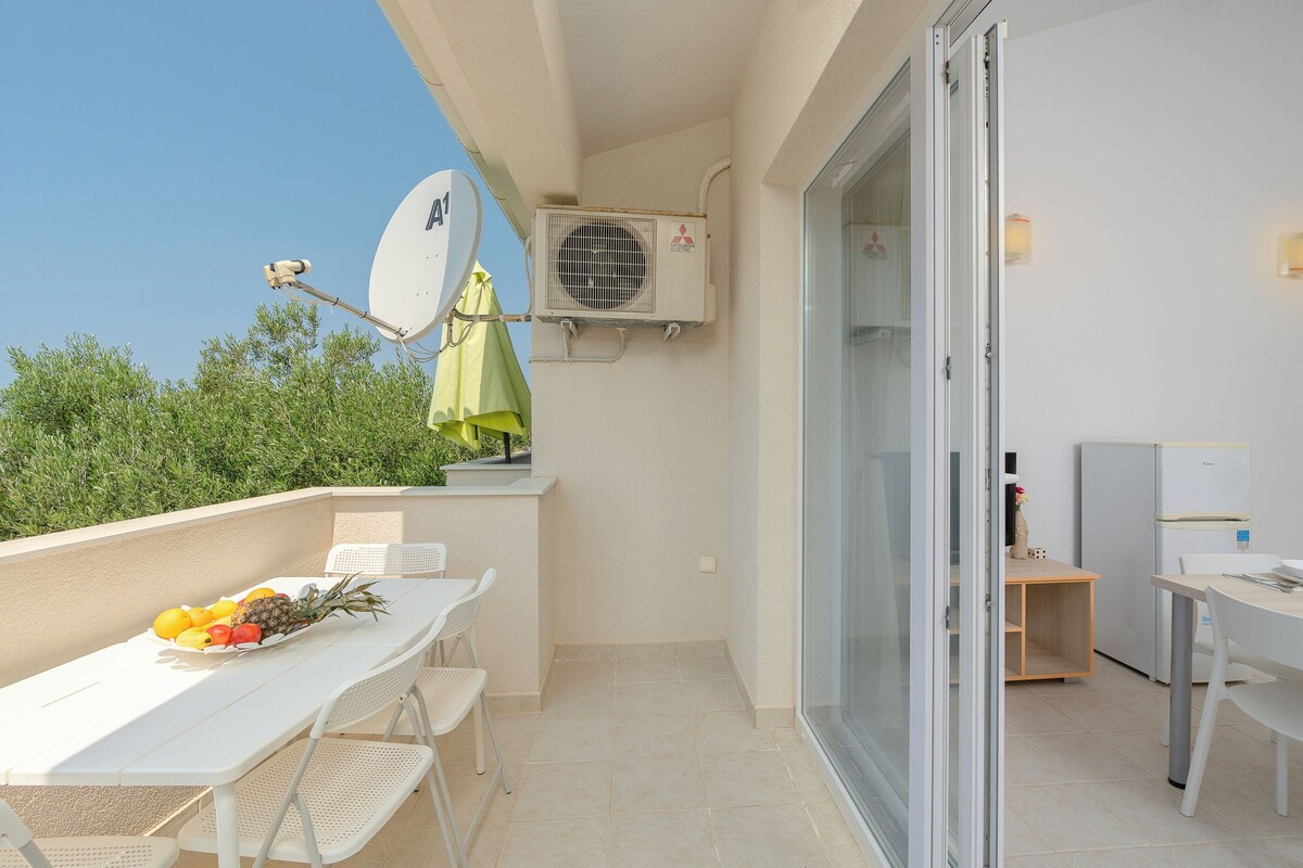 Ein Balkon mit Tisch, bedeckt mit Früchten, einer Sat-Schüssel und einem kleinen Kühlschrank.