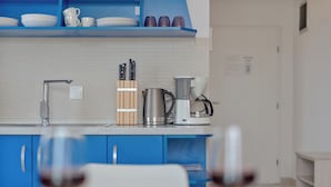 A modern kitchen with blue cabinets, a coffee maker, and a knife block. - Apartments Marina (Novalja)