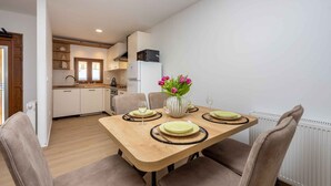 Un comedor con una mesa de madera dispuesta para cuatro personas, rodeada de sillas. Un jarrón con flores está sobre la mesa.