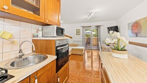 Une cuisine avec des meubles de rangement en bois, un four à micro-ondes, un évier et un plan de travail.
