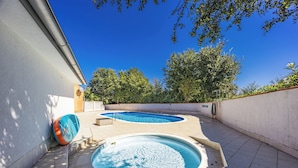 Un espace piscine comprenant deux bassins, un plongeoir et un mur avec une fenêtre.