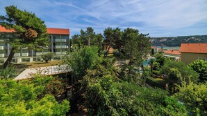 A hotel with multiple floors, outdoor swimming pool, and lush greenery. - Apartments Anica J (Lopar)