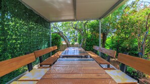 A covered outdoor seating area with benches and a pathway. - Apartments Anica J (Lopar)