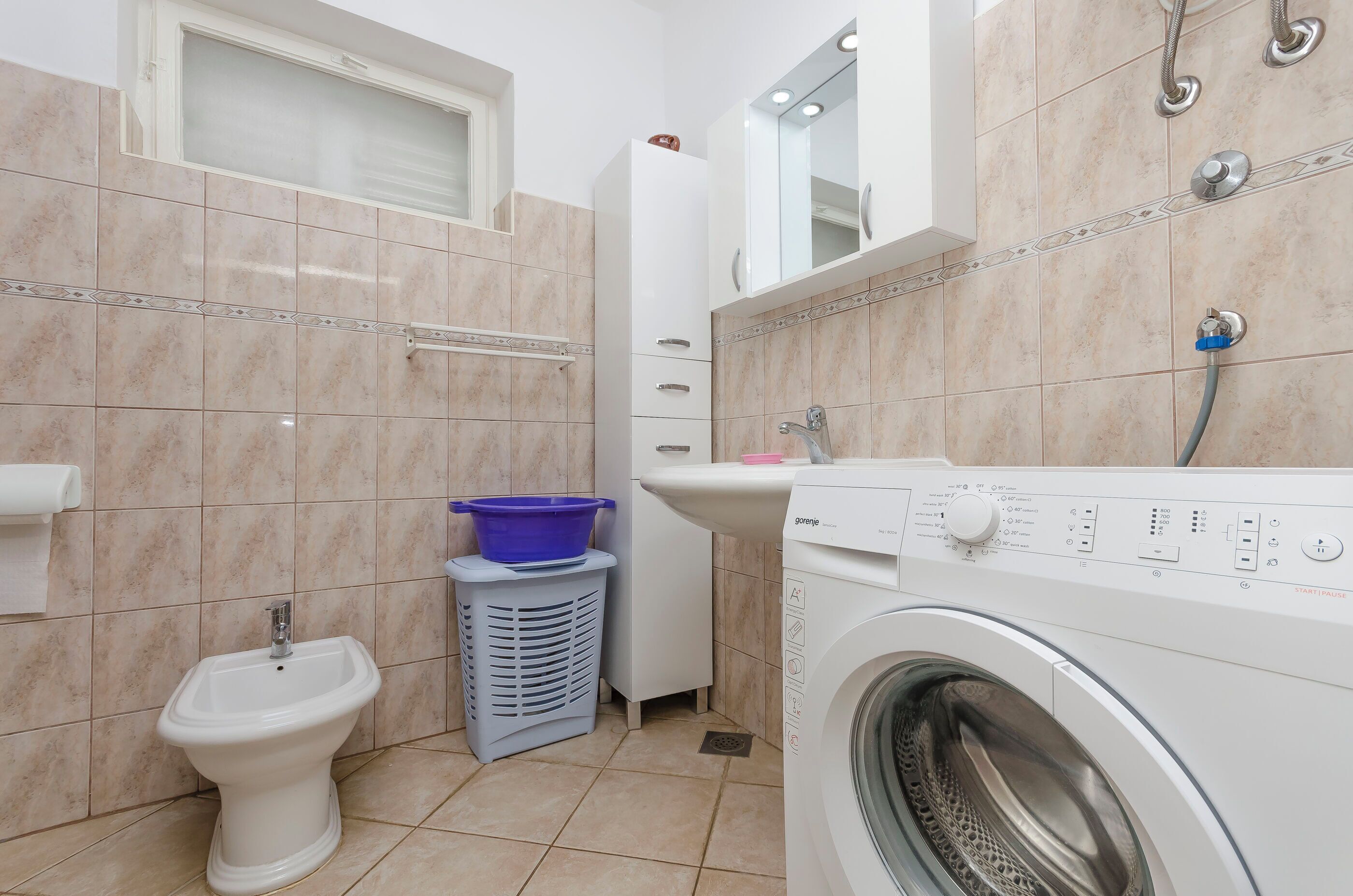 Een moderne badkamer met toilet, wasmachine en wastafel.