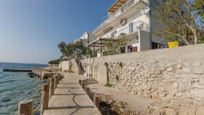 Un edificio costero con muro de piedra, escalones de madera y vista al mar.