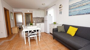 A compact living space with a dining area, kitchenette, and a sofa with a yellow pillow. - Apartment Marigold (Sveti Filip i Jakov)