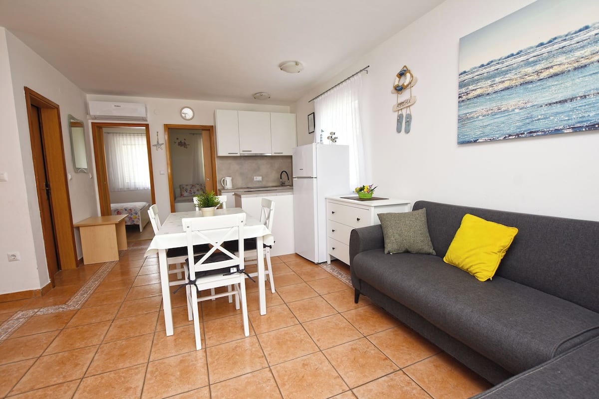 A compact living space with a dining area, kitchenette, and a sofa with a yellow pillow.