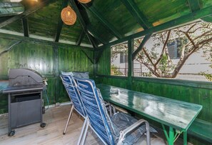 An outdoor seating area with a green bench, a grill, and folding chairs. - Apartment Marigold (Sveti Filip i Jakov)