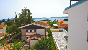 A residential area with a house featuring a tiled roof, a balcony, and a view of the sea. - Apartment Marigold (Sveti Filip i Jakov)