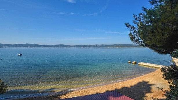 A clear view of a beach with calm waters, a distant shoreline, and a clear sky. - Apartment Marigold (Sveti Filip i Jakov)