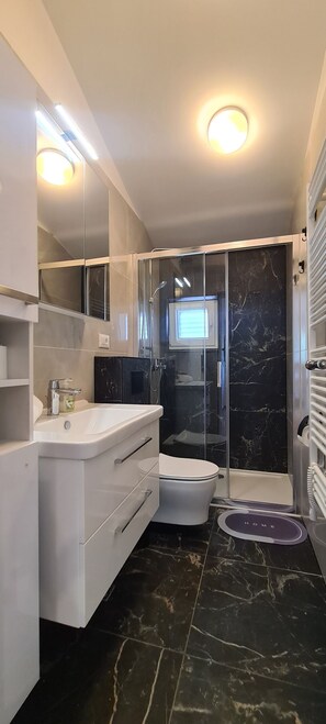A modern bathroom with a white vanity, a glass shower enclosure, and a marble floor. - Apartments Hvaranin (Stari Grad)