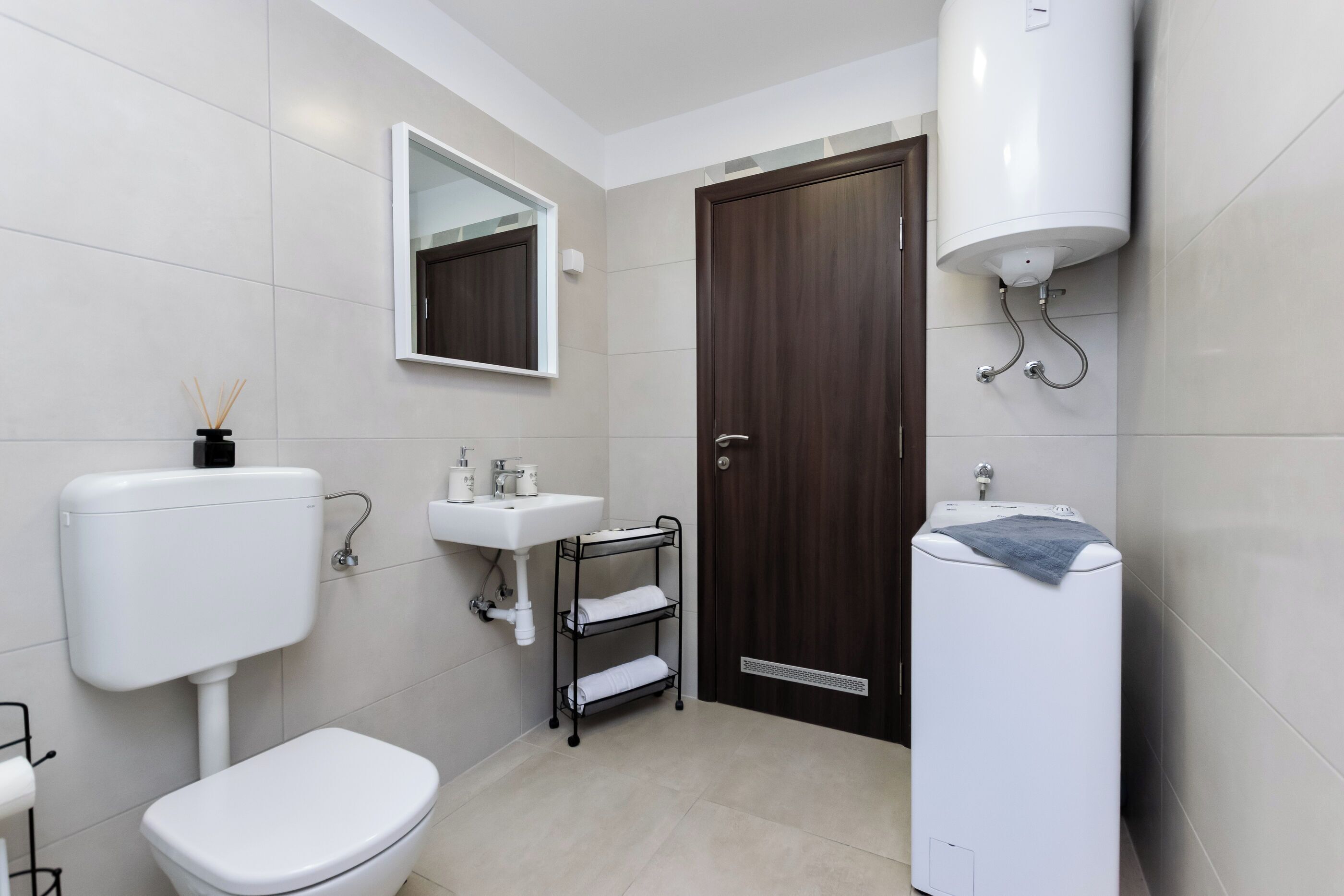 A modern bathroom with a toilet, sink, mirror, and towel rack.