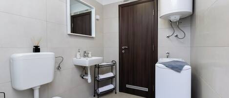 A modern bathroom with a toilet, sink, mirror, and towel rack.