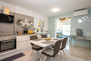 A modern kitchen with a built-in oven and microwave, a dining area with a table and chairs, and a living area with a sofa and decorative wall art. - Apartment Beautifull View (Labin)