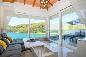 Un salon moderne avec un canapé, une table basse et une vue sur un lac et des collines.