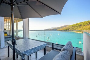 A balcony with a table and chairs, overlooking a turquoise sea with boats. - Apartment Beautifull View (Labin)