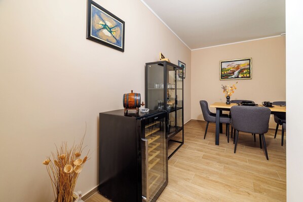 A dining area with a wooden table, chairs, a black cabinet, and a vase with dried plants. - Apartment Slavko (Rab)