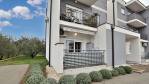 Ein modernes Wohnhaus mit zwei Etagen, Balkonen, einer überdachten Eingangspartei und einem angelegten Garten.