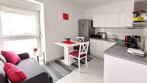 A compact living space with a kitchenette, a dining area, and a seating area with a sofa and chairs. - Apartment Oliva (Knin)