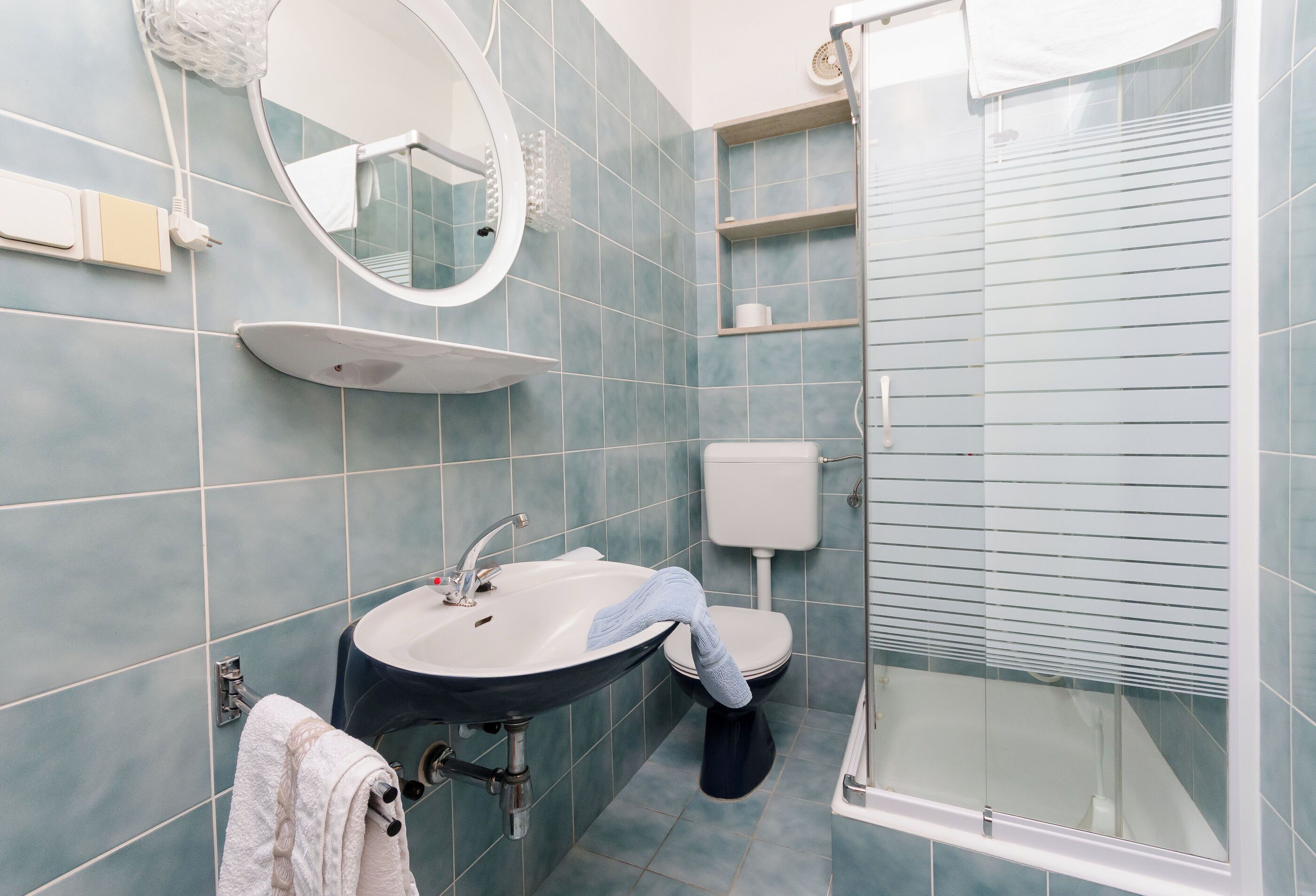 A bathroom with a sink, mirror, toilet, and shower.