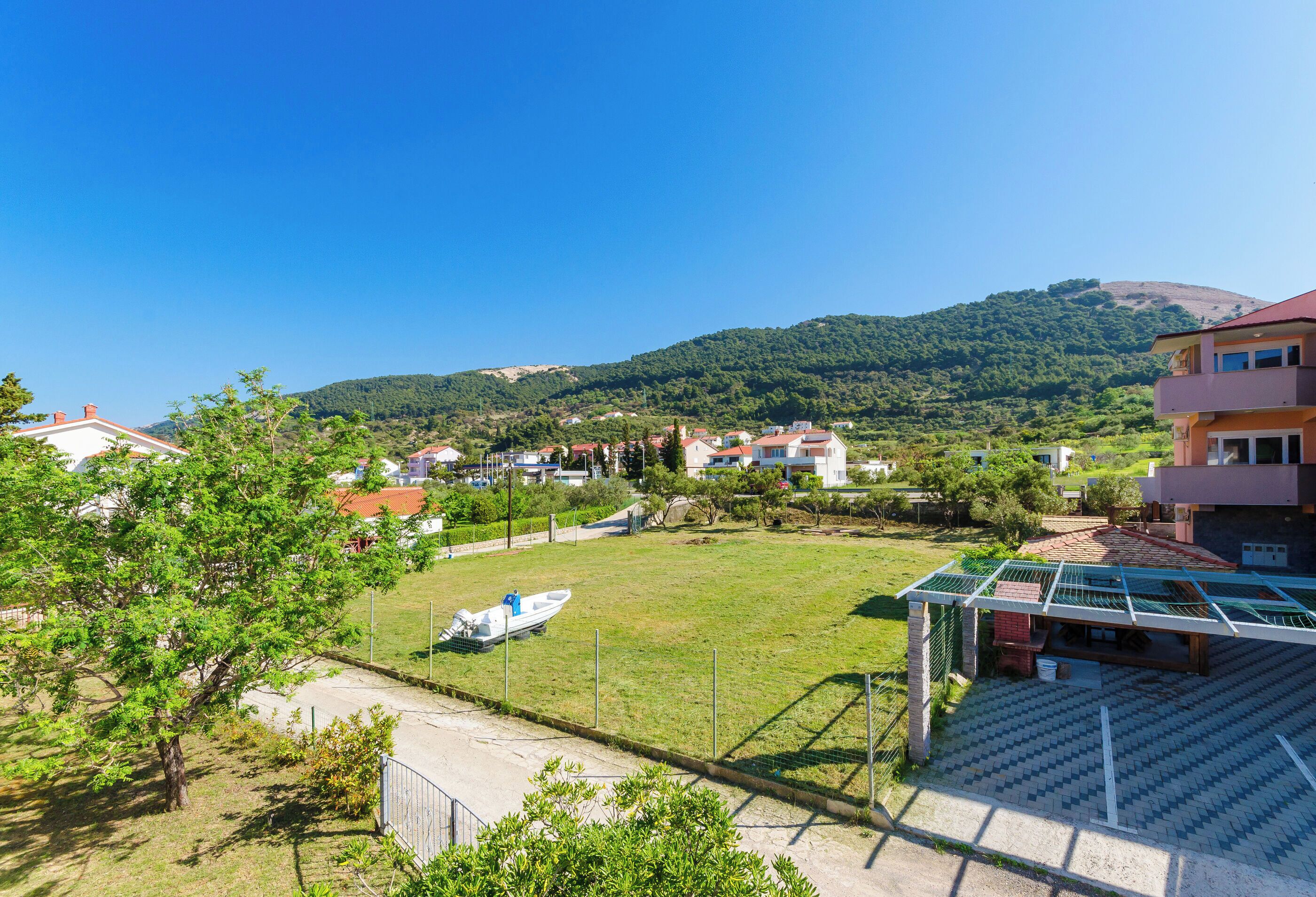 A residential area with houses, a boat, and a hill in the background.