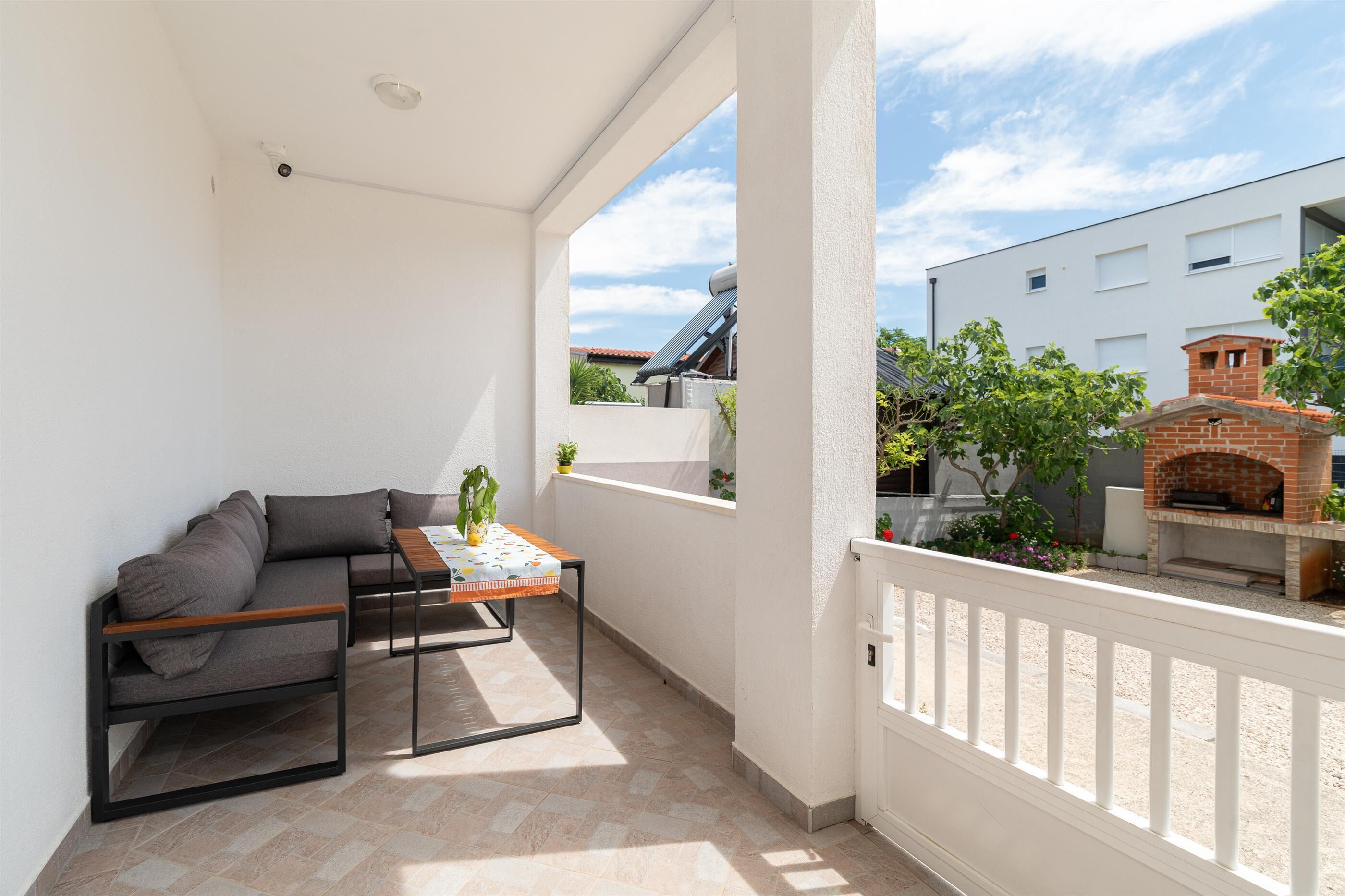 Ein Balkon mit einer Couch, einem Tisch und einem Blumentopf.