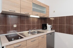 A kitchen with wooden cabinets, a stainless steel sink, a coffee maker, and a dishwasher. - Apartments Ivica (Vir)