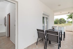 Un balcone con tavolo e sedie, una porta e una finestra.