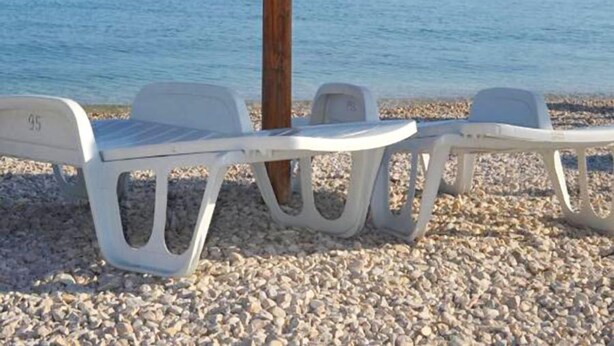 A beach with a wooden umbrella and white plastic chairs. - Apartments Ivica (Vir)