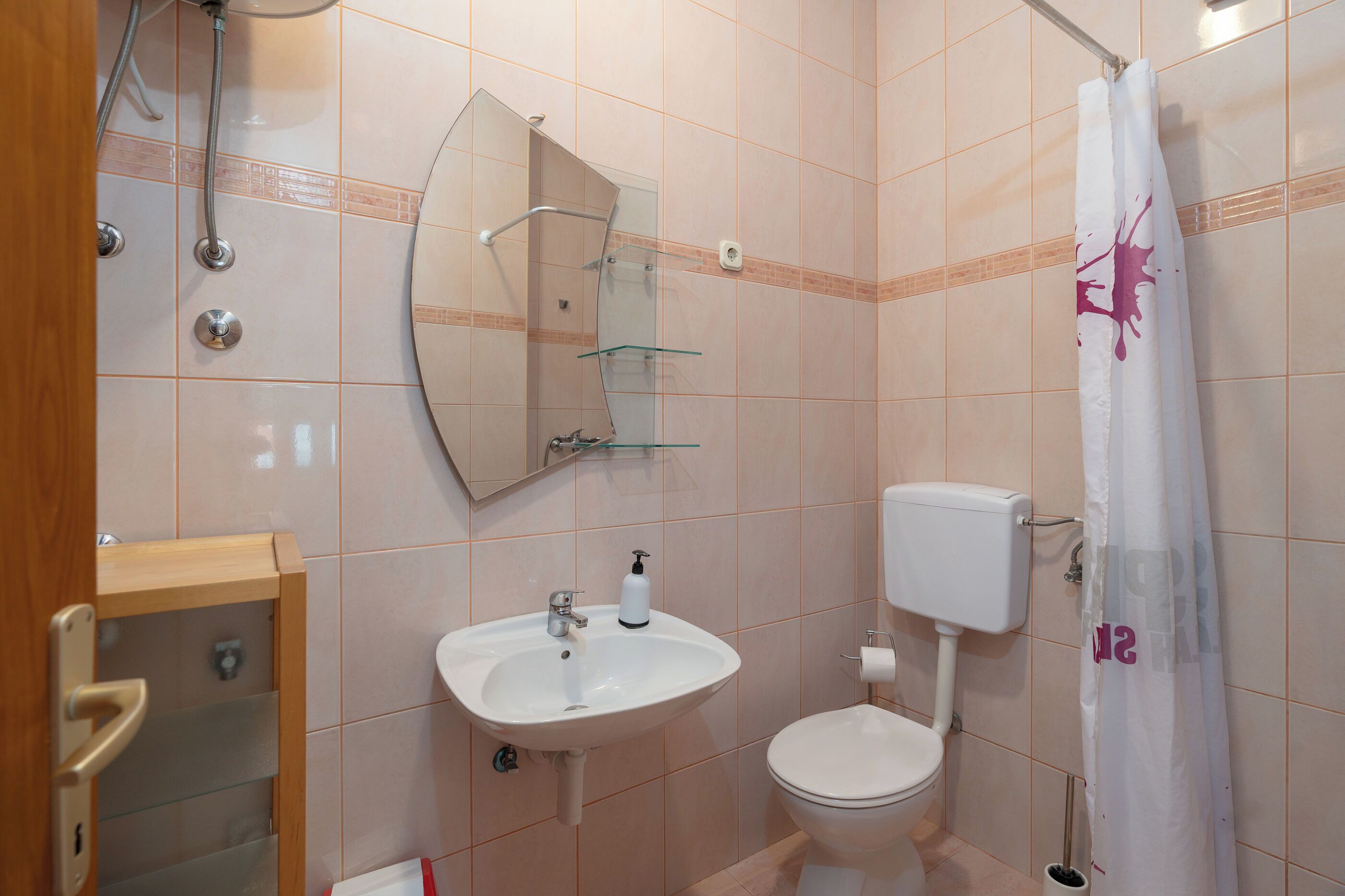 A bathroom with a white sink, toilet, and shower curtain.