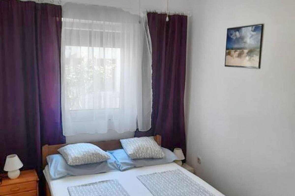 A bedroom with a bed, a ceiling fan, a nightstand, and a wall-mounted picture.