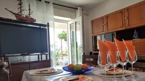 Zona de menjador amb una taula preparada per a quatre, un model de vaixell a la paret i vista a l'exterior.