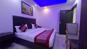 Un dormitorio con cama, mesita de noche, silla, un cuadro en la pared y una puerta.