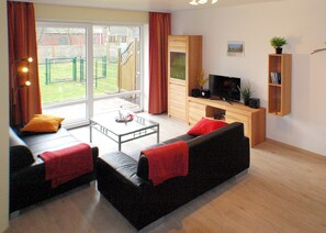 A modern living room with a sofa set, a coffee table, a TV, and a bookshelf.