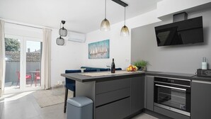 A modern kitchen with a central island, built-in oven, and pendant lighting. - House Luxury Konforta (Sibenik)