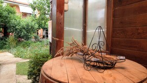 Een houten tafeltje met een metalen mand waarin gedroogde planten en een klein boek liggen.