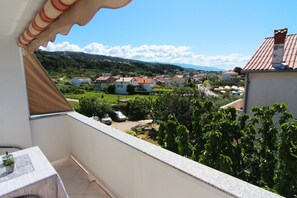 A balcony with a view of a residential area, including houses and greenery. - Apartments Biserka G (Rab)