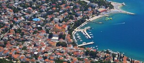 Vista aérea de uma cidade costeira com habitação densa, um porto de iates e uma área de praia.