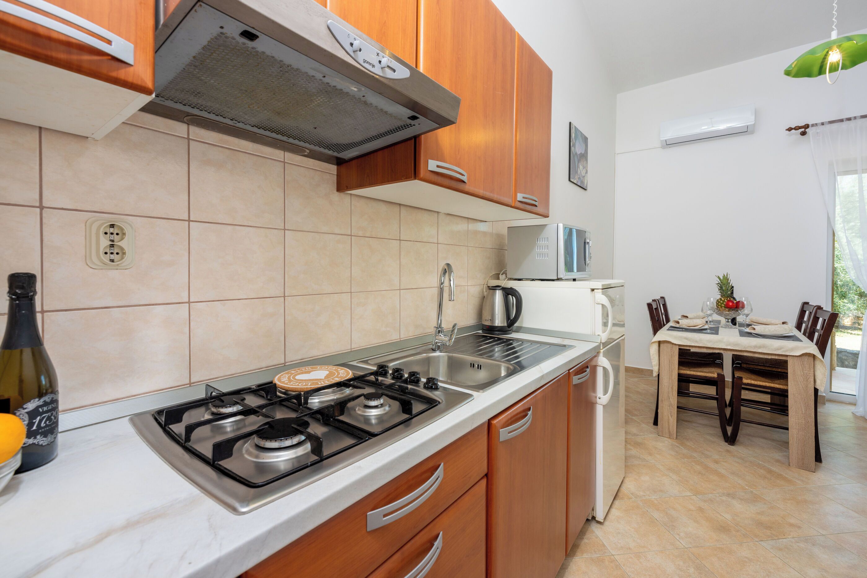 A kitchen with a gas stove, sink, and wooden cabinets.
