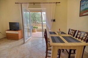 A dining area with a table, chairs, and a television on a cabinet. - Apartment David (Liznjan)