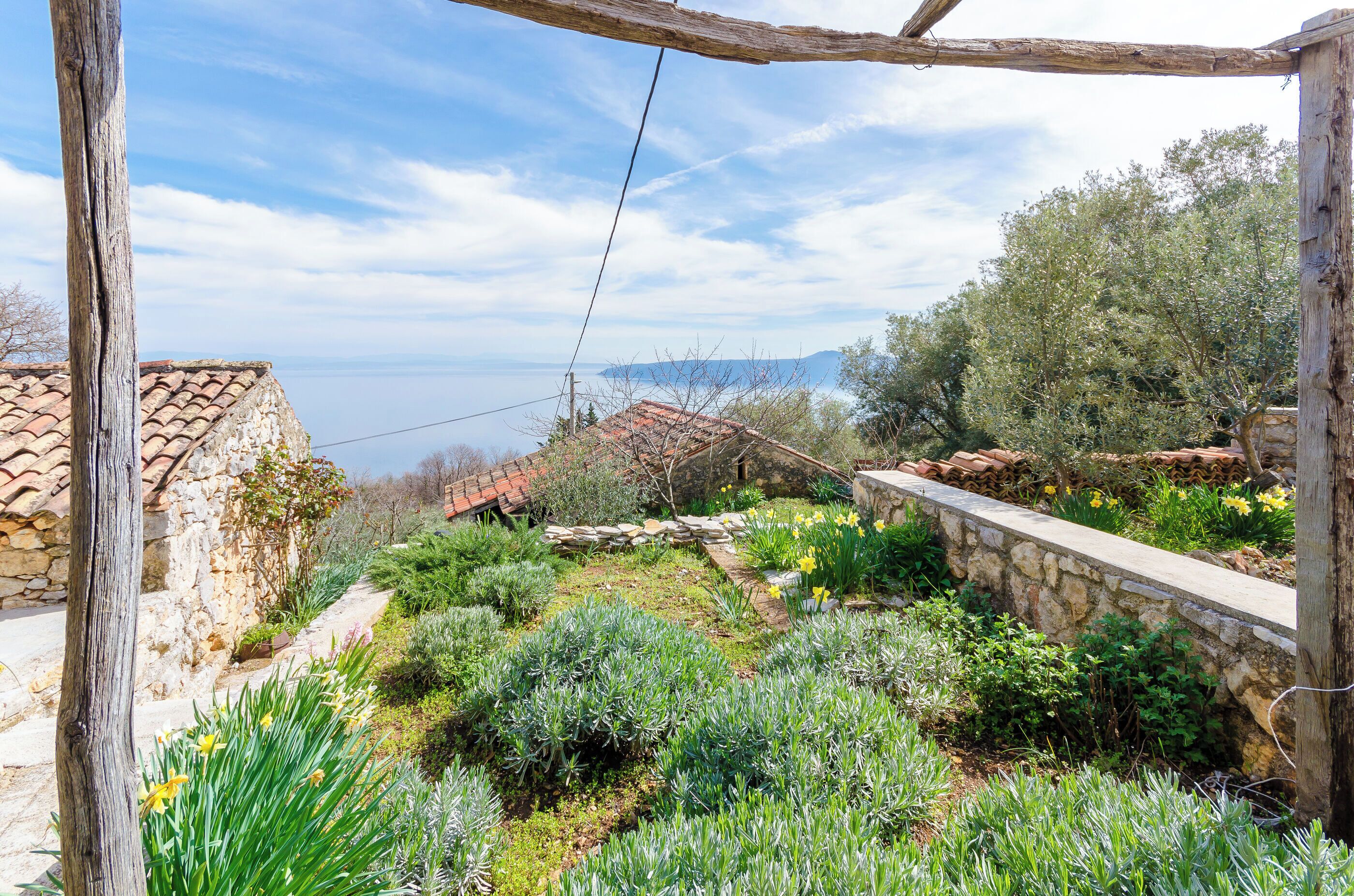 A garden with stone walls, various plants, and a view of distant mountains.