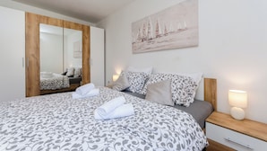 Un letto ben rifatto con una coperta a fantasia, un comodino con una lampada e un grande specchio sull'armadio.
