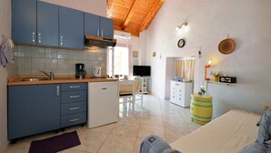 A compact kitchen with blue cabinets, a white refrigerator, and a wooden ceiling. - Apartments Sunce (Murter-Kornati)