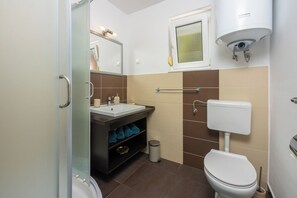 Une salle de bain moderne avec une douche à parois de verre, des toilettes blanches, un lavabo avec un miroir et un porte-serviettes.