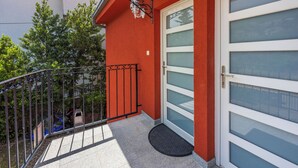 En rød facade med en glasdør og en lille balkon med gelænder.