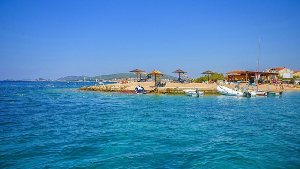 A beach with clear blue water, umbrellas, and boats. - Apartment More (Vodice)